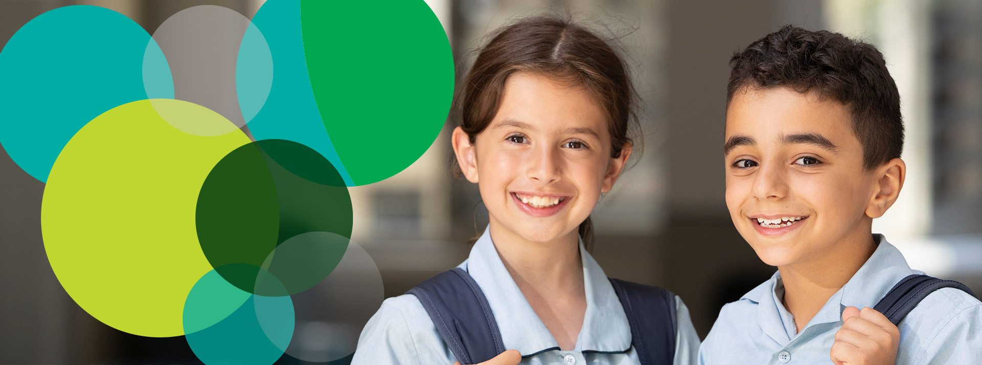 Two happy students from St Patrick's Primary School Guildford. The students are standing in the classroom and are wearing their backpacks.