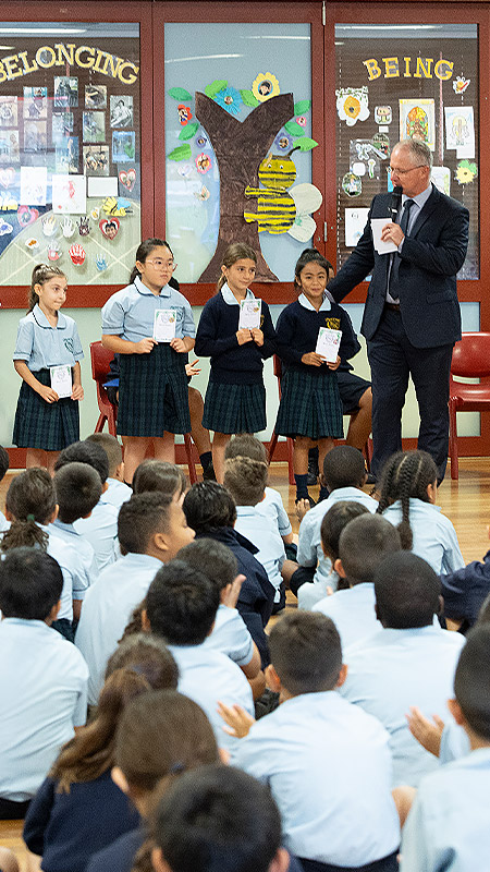 St Patrick's Catholic Primary Guildford School Assembly. Kevin Jones is presenting merit award to students.