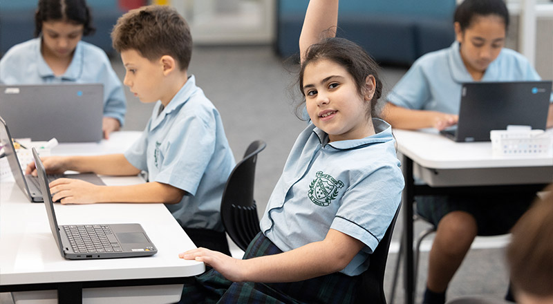 St Patrick's Primary Guildford student with hand raised, she is using a laptop