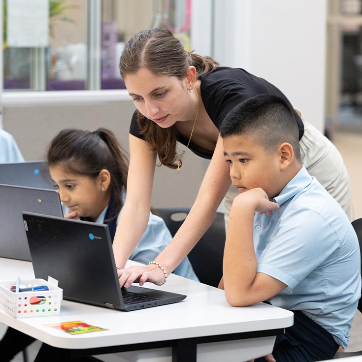 Three St Pat's Guildford students in class, being assisted by their teacher